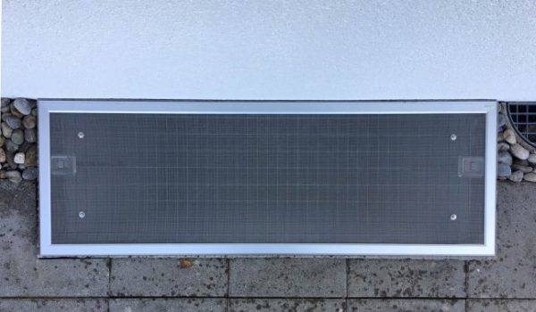 Lichtschachtabdeckung liegt auf einem Kellerschacht an der Hauswand