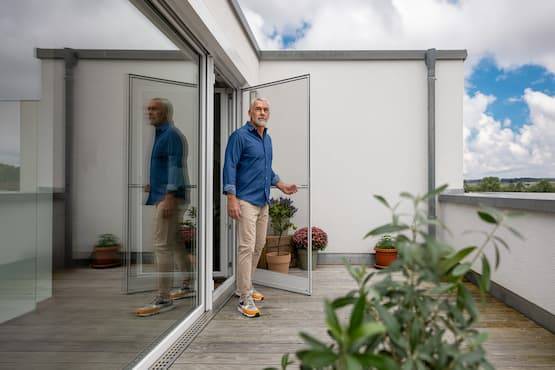 Mann öffnet eine Neher Fliegengitter Drehtür